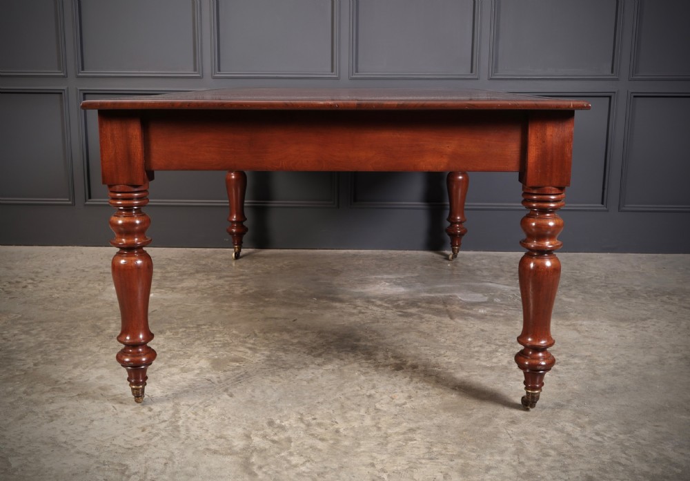 A Victorian mahogany partners writing table with a rich red leather inlaid top, frieze drawers, and turned legs set on brass castors. View XI