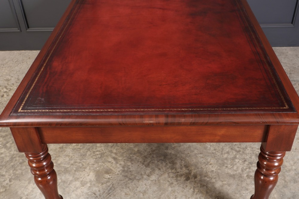 A Victorian mahogany partners writing table with a rich red leather inlaid top, frieze drawers, and turned legs set on brass castors. View XII
