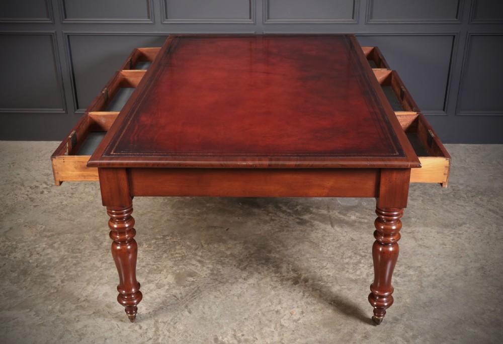 A Victorian mahogany partners writing table with a rich red leather inlaid top, frieze drawers, and turned legs set on brass castors. View XIII