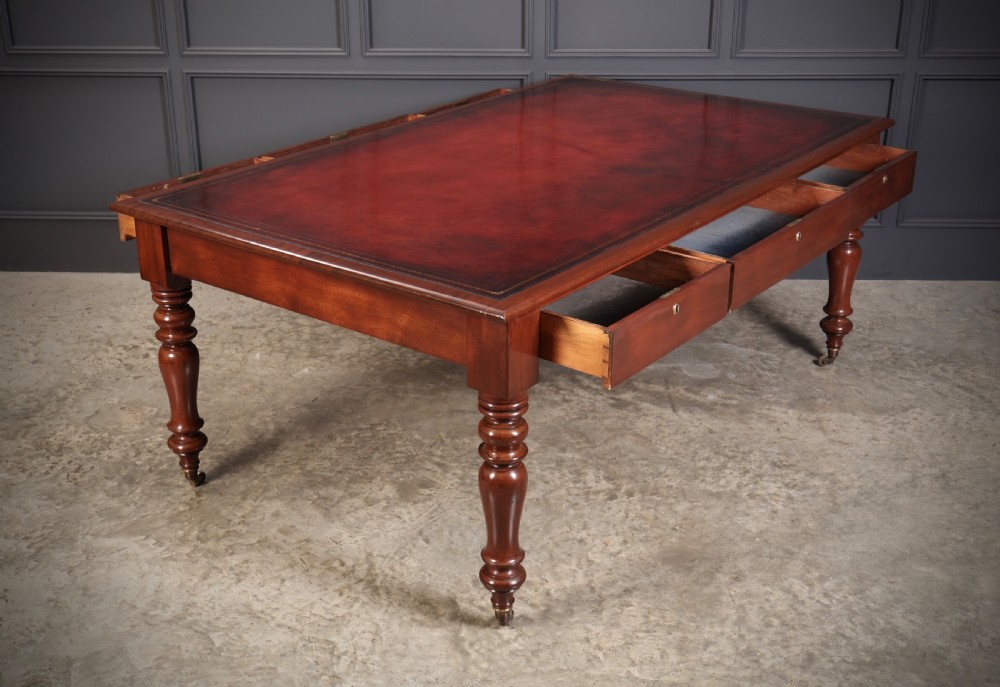 A Victorian mahogany partners writing table with a rich red leather inlaid top, frieze drawers, and turned legs set on brass castors. View XIV