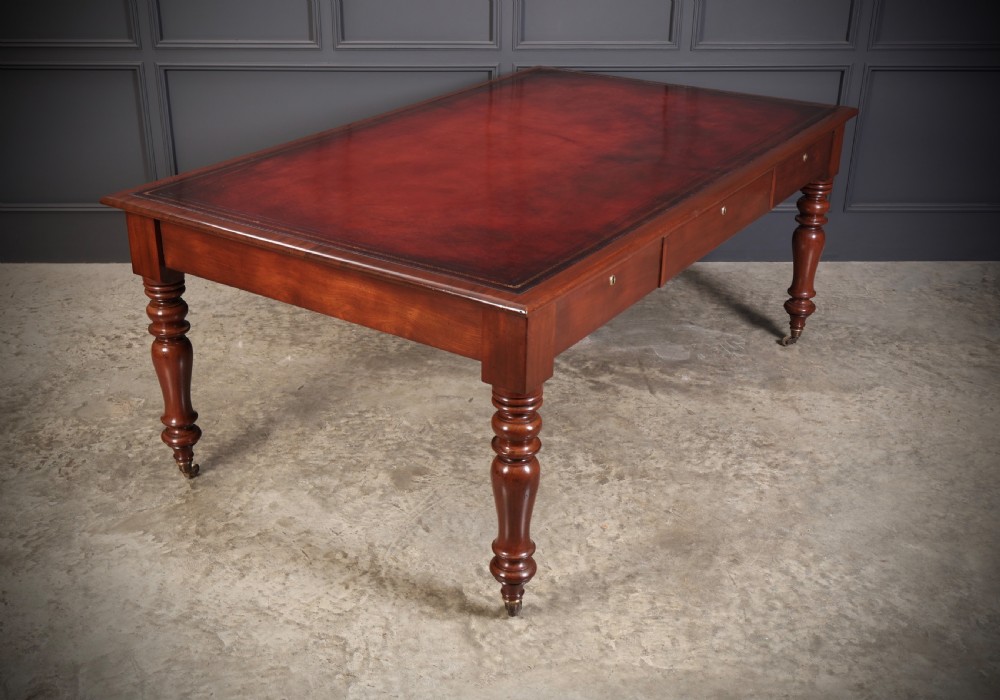A Victorian mahogany partners writing table with a rich red leather inlaid top, frieze drawers, and turned legs set on brass castors. View XV