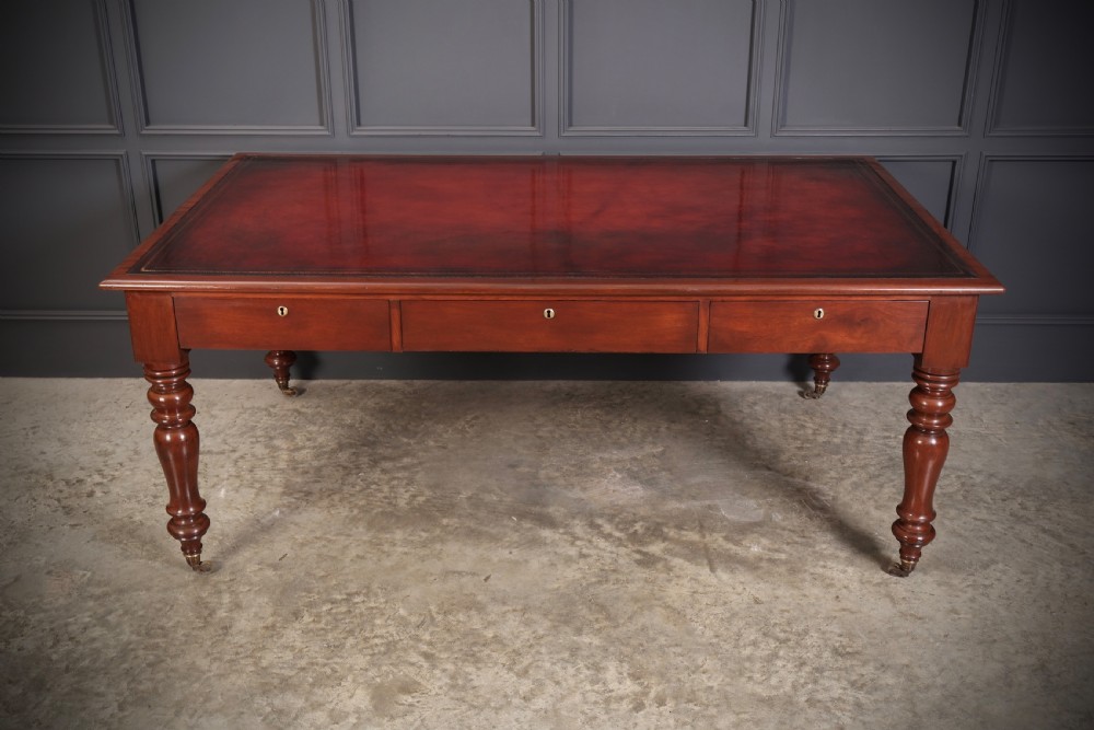 A Victorian mahogany partners writing table with a rich red leather inlaid top, frieze drawers, and turned legs set on brass castors. View XVI