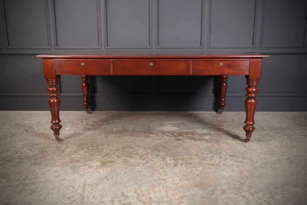 A Victorian mahogany partners writing table with a rich red leather inlaid top, frieze drawers, and turned legs set on brass castors. View XVII