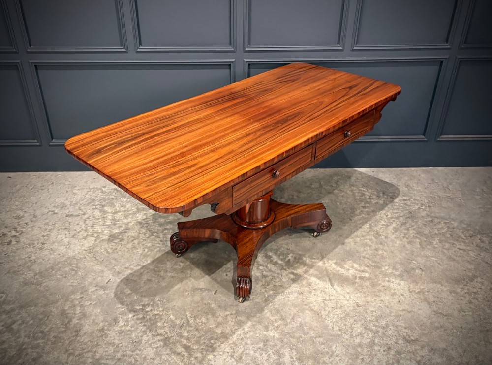 A 19th-century Goncalo Alves library table featuring a polished rectangular top with rounded corners, frieze drawers, and a central turned pedestal on a quadform base with scroll feet. View III