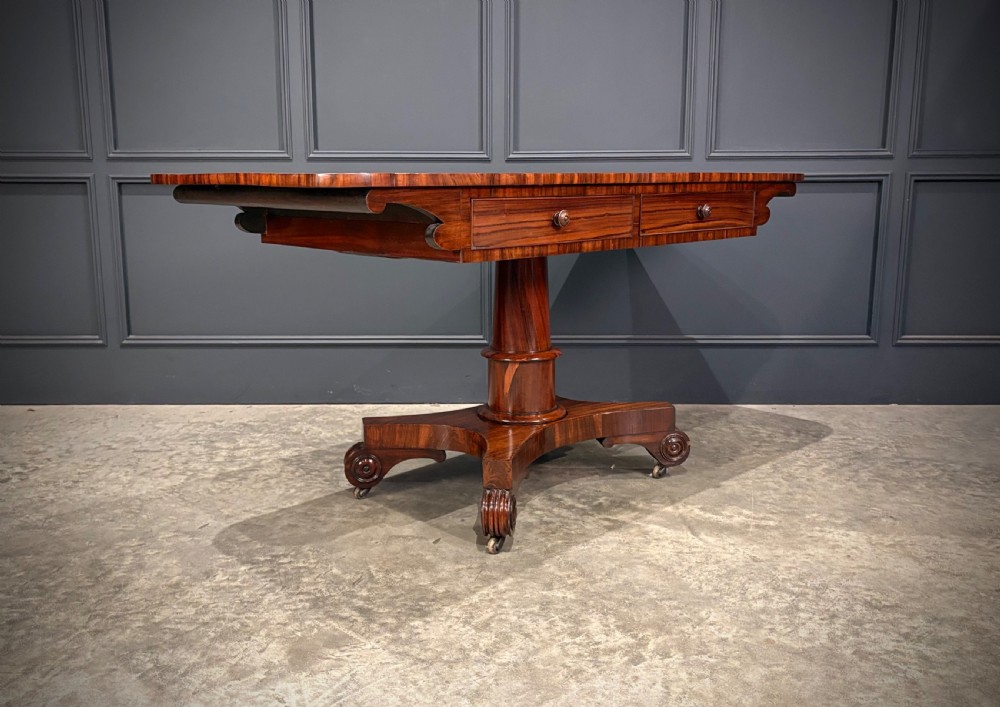 A 19th-century Goncalo Alves library table featuring a polished rectangular top with rounded corners, frieze drawers, and a central turned pedestal on a quadform base with scroll feet. View II