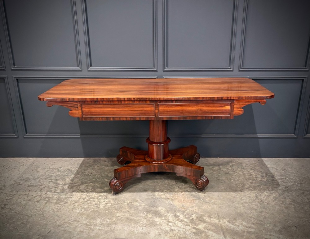 A 19th-century Goncalo Alves library table featuring a polished rectangular top with rounded corners, frieze drawers, and a central turned pedestal on a quadform base with scroll feet. View XI