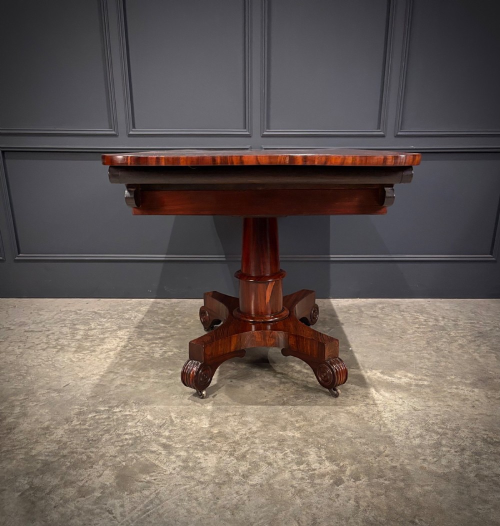 A 19th-century Goncalo Alves library table featuring a polished rectangular top with rounded corners, frieze drawers, and a central turned pedestal on a quadform base with scroll feet. View XII