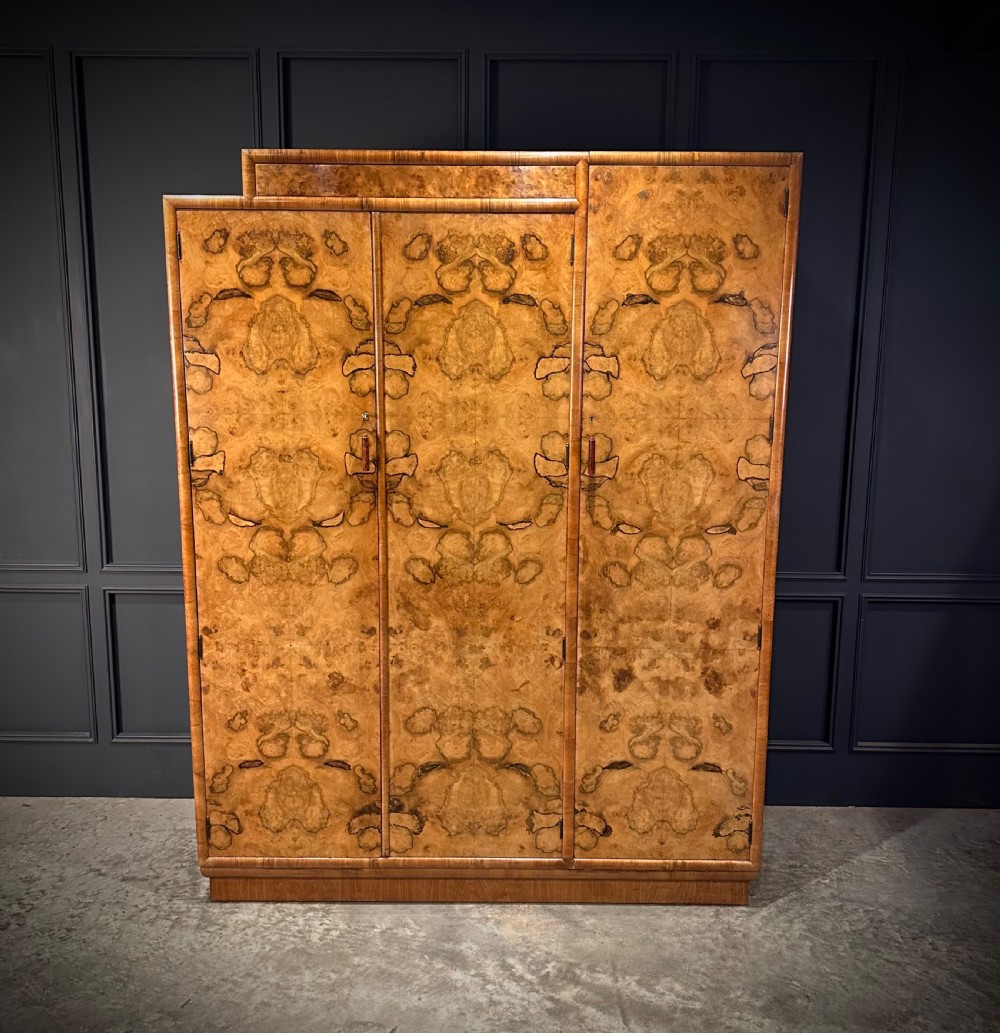 A tall three-door Art Deco wardrobe crafted from figured burr walnut with a stepped top cornice and plinth base. View II