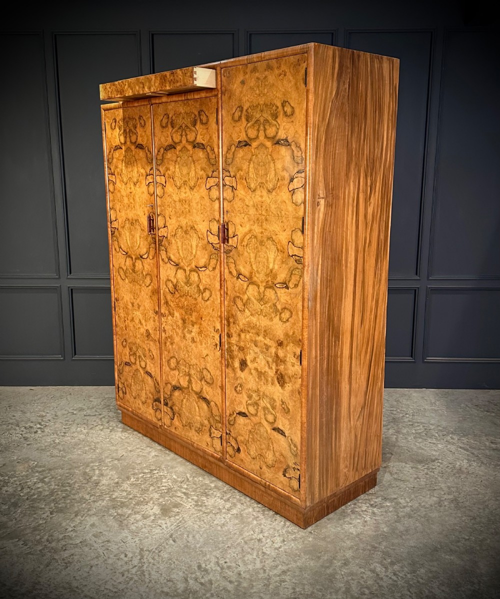 A tall three-door Art Deco wardrobe crafted from figured burr walnut with a stepped top cornice and plinth base. View V