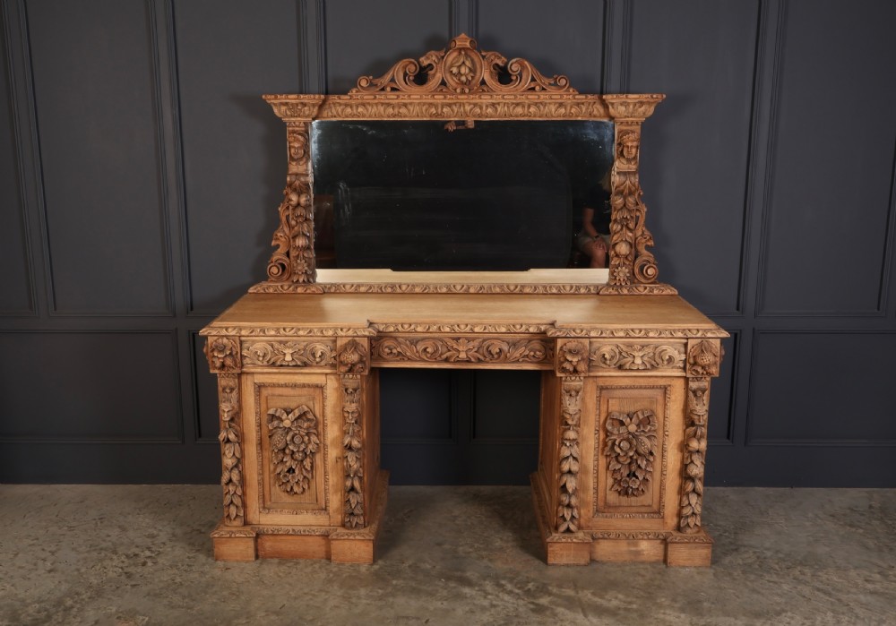 A large bleached oak pedestal sideboard featuring elaborate fruit swags, carved mask details, twin lower cupboards, and an integrated rectangular mirror superstructure. View III