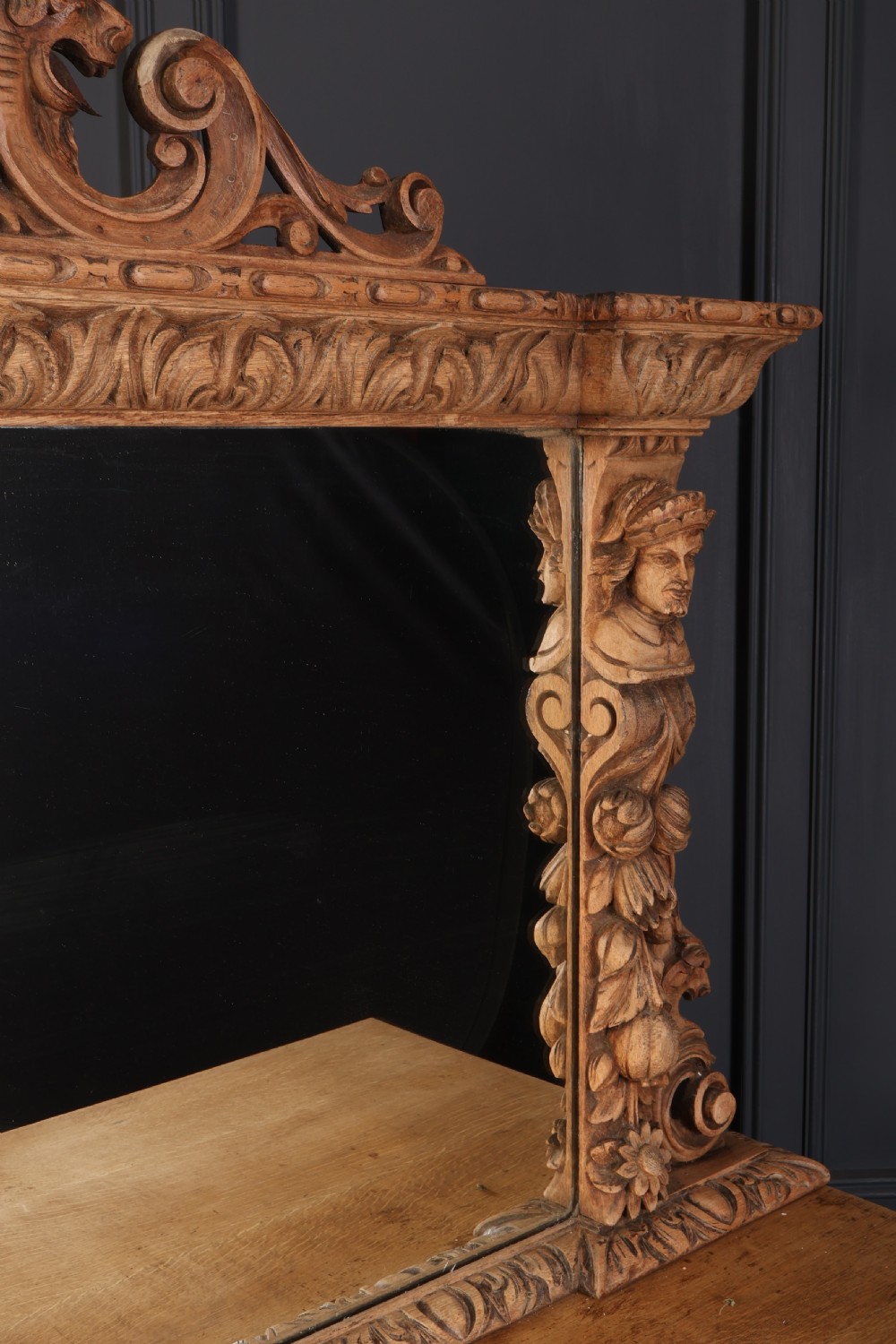 A large bleached oak pedestal sideboard featuring elaborate fruit swags, carved mask details, twin lower cupboards, and an integrated rectangular mirror superstructure. View IV