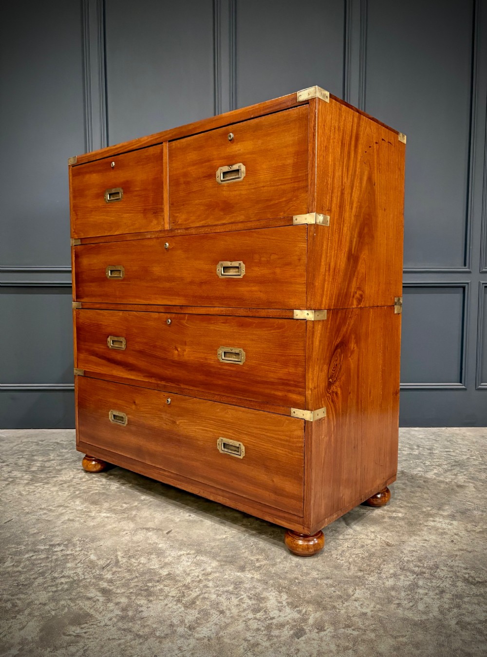 A Victorian mahogany military campaign chest featuring two stackable sections, brass corner brackets, flush recessed handles, and turned bun feet.