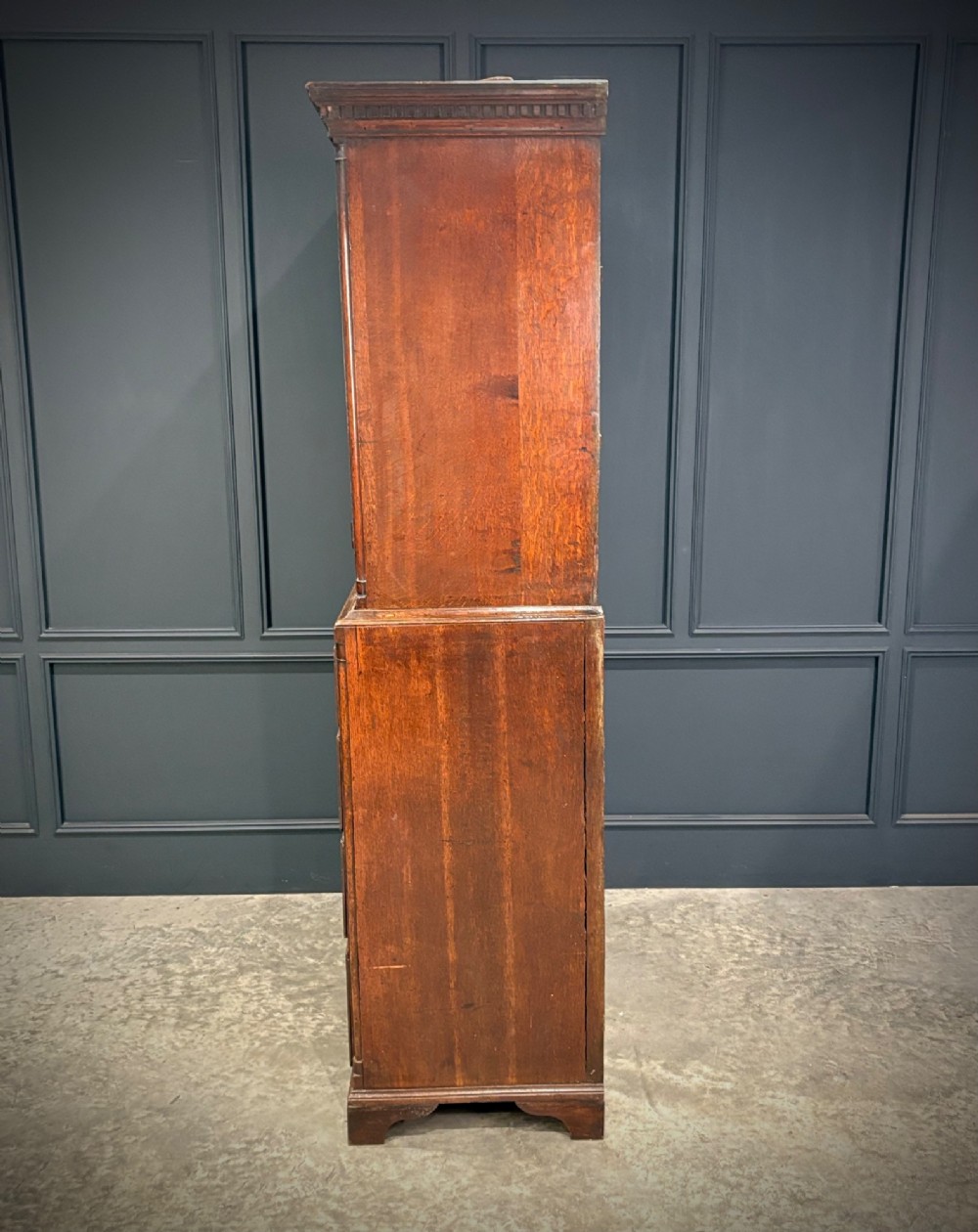 An 18th-century carved dark oak housekeepers cupboard featuring upper panel doors with geometric lozenge carving above a base with five carved drawers. View IX