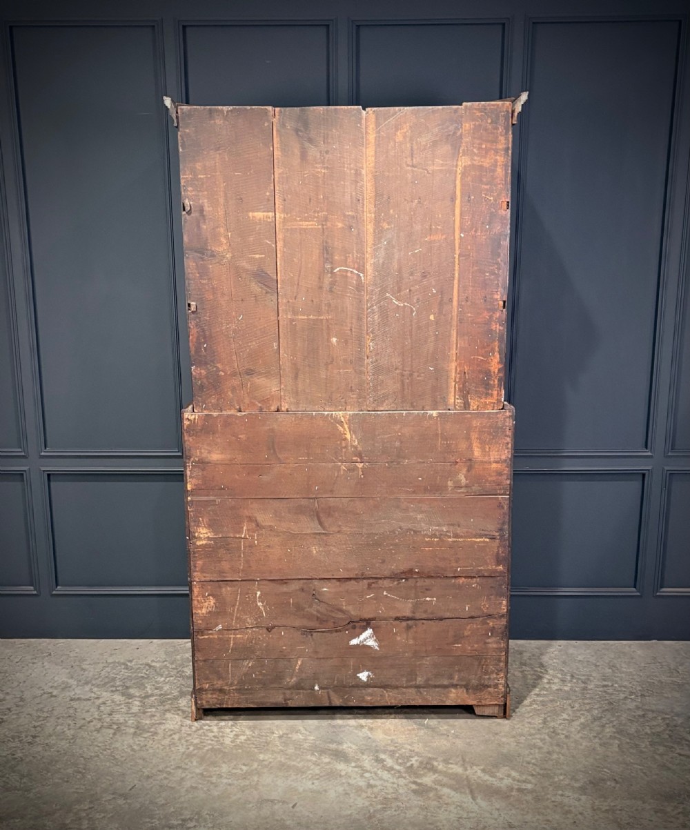 An 18th-century carved dark oak housekeepers cupboard featuring upper panel doors with geometric lozenge carving above a base with five carved drawers. View X