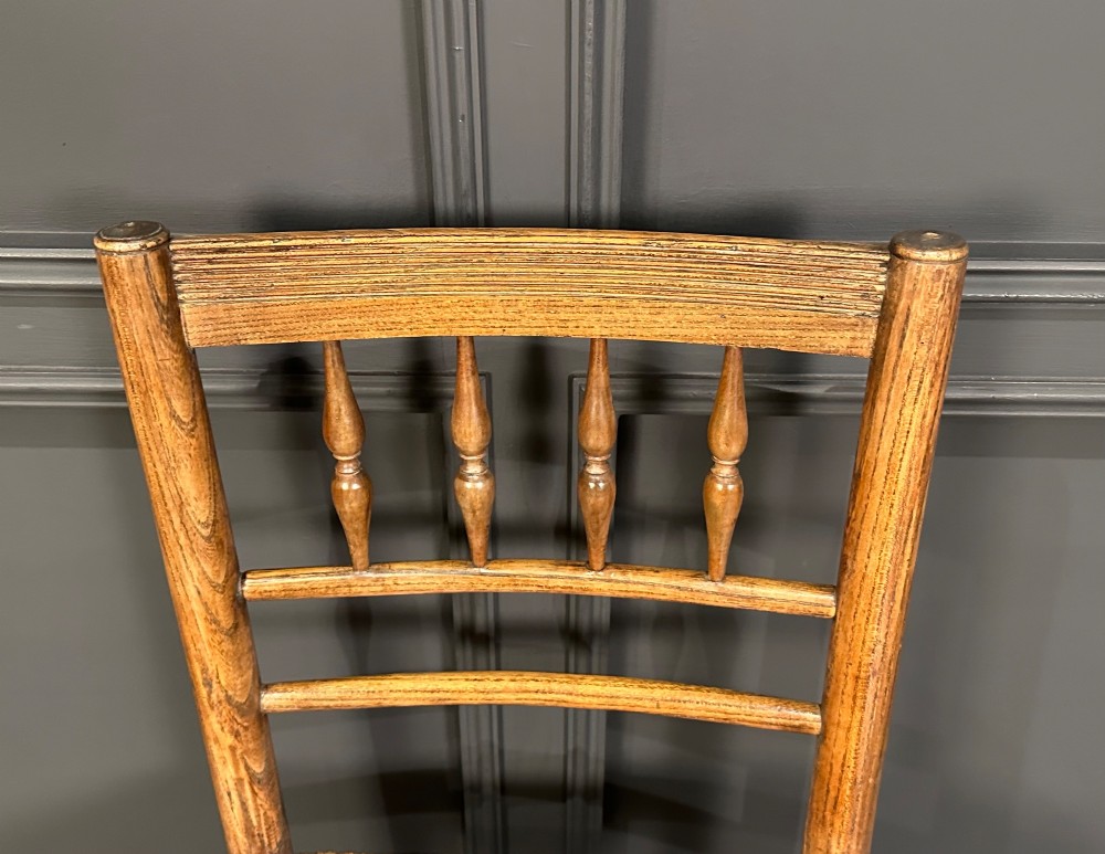 An 18th-century country elm side chair featuring a woven rush seat, turned spindle backrest, and turned wood legs connected by stretchers. View IV