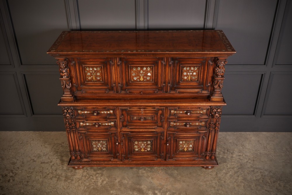 A two-tiered dark walnut sideboard featuring geometric mother of pearl inlays, hand-carved figurative relief accents, drawers, and panelled cabinet doors. View III