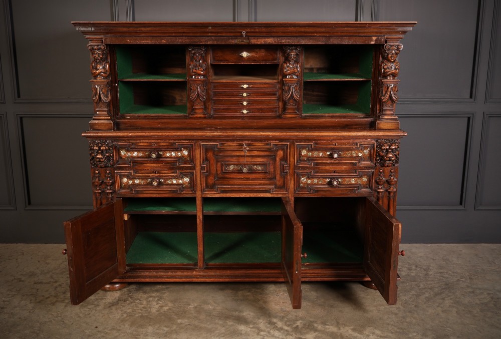 A two-tiered dark walnut sideboard featuring geometric mother of pearl inlays, hand-carved figurative relief accents, drawers, and panelled cabinet doors. View IV
