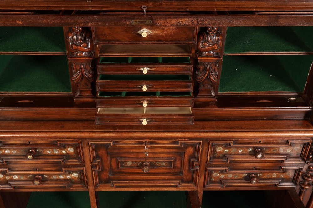 A two-tiered dark walnut sideboard featuring geometric mother of pearl inlays, hand-carved figurative relief accents, drawers, and panelled cabinet doors. View V