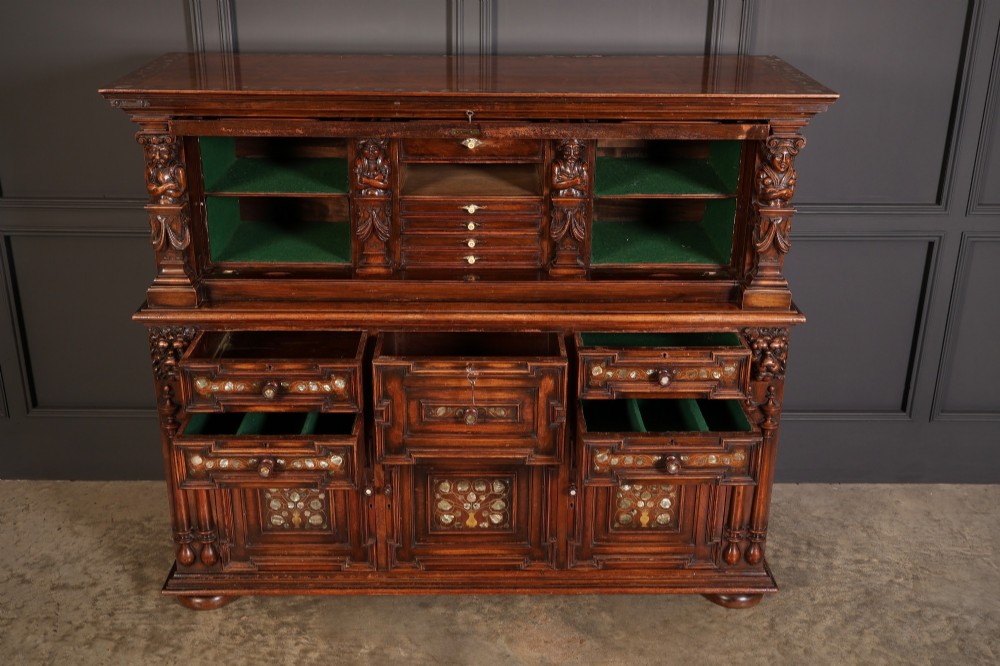 A two-tiered dark walnut sideboard featuring geometric mother of pearl inlays, hand-carved figurative relief accents, drawers, and panelled cabinet doors. View VI