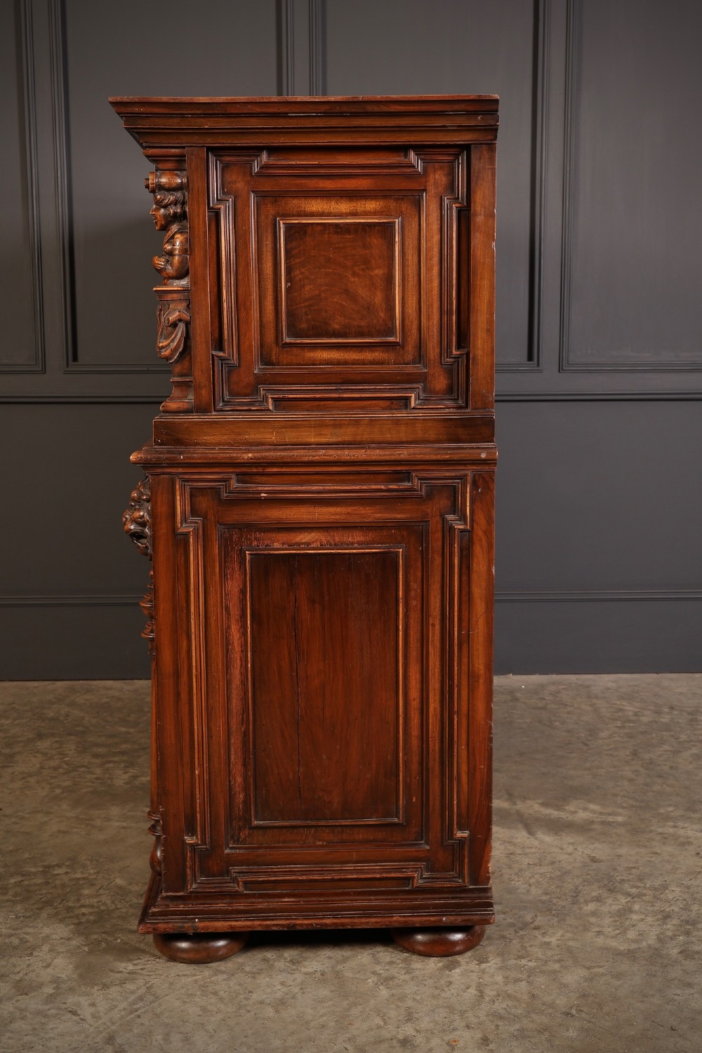 A two-tiered dark walnut sideboard featuring geometric mother of pearl inlays, hand-carved figurative relief accents, drawers, and panelled cabinet doors. View VIII