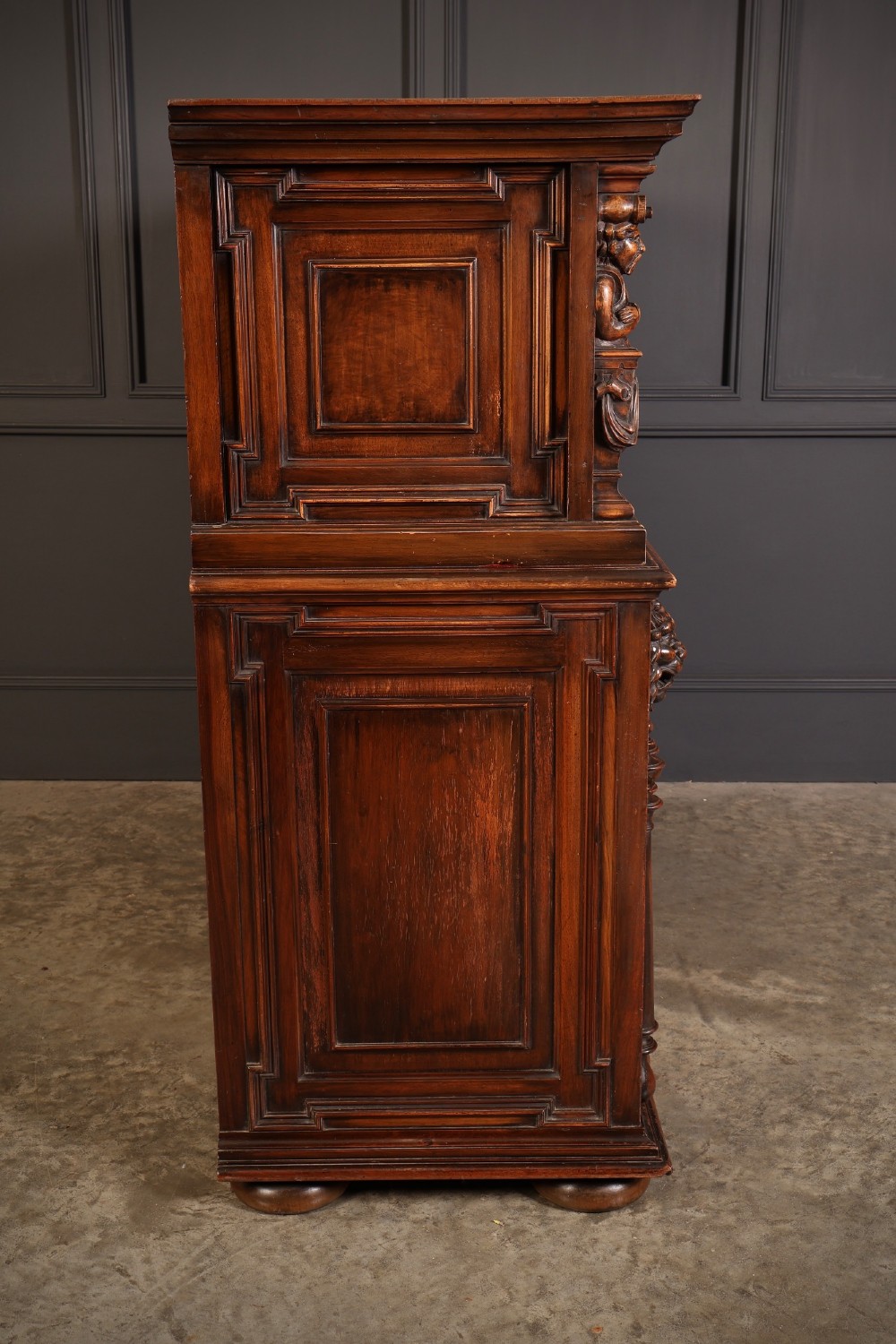 A two-tiered dark walnut sideboard featuring geometric mother of pearl inlays, hand-carved figurative relief accents, drawers, and panelled cabinet doors. View X