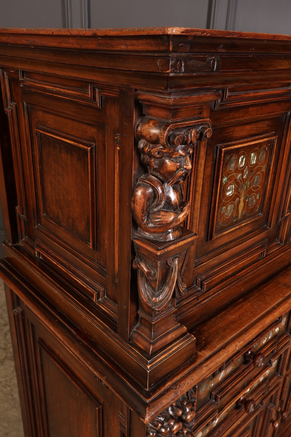 A two-tiered dark walnut sideboard featuring geometric mother of pearl inlays, hand-carved figurative relief accents, drawers, and panelled cabinet doors. View XI