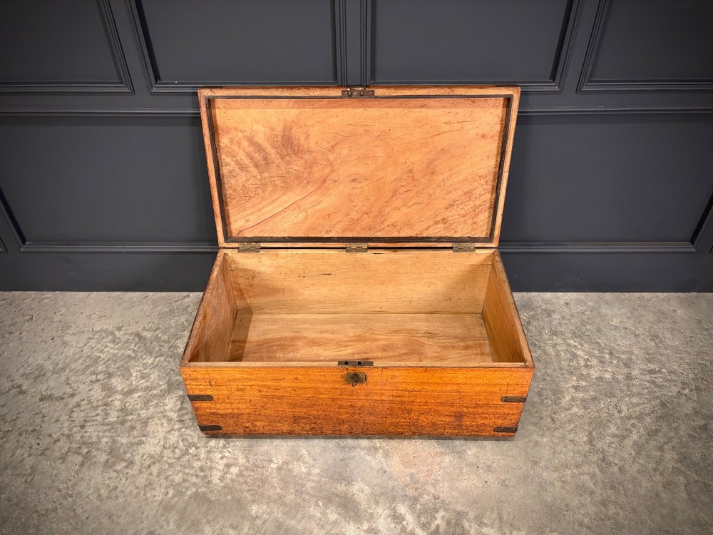A rectangular 19th-century camphor wood trunk featuring brass corner bindings, side carrying handles, and a central brass lock plate. View V