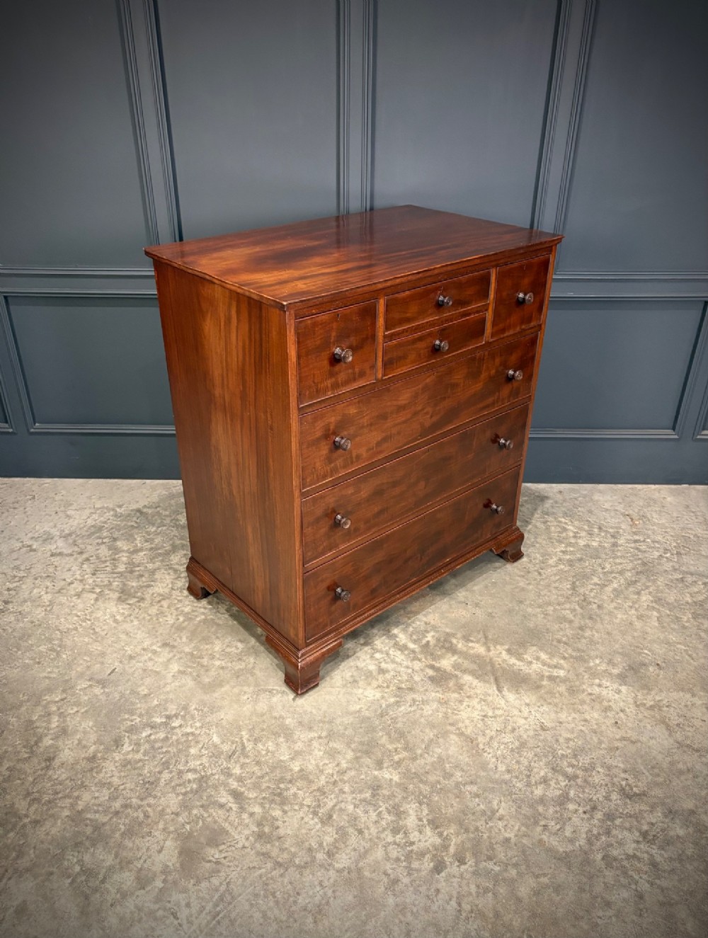 A tall antique mahogany chest of drawers featuring an upper arrangement of small drawers over three graduated full-width drawers, resting on bracket feet. View II