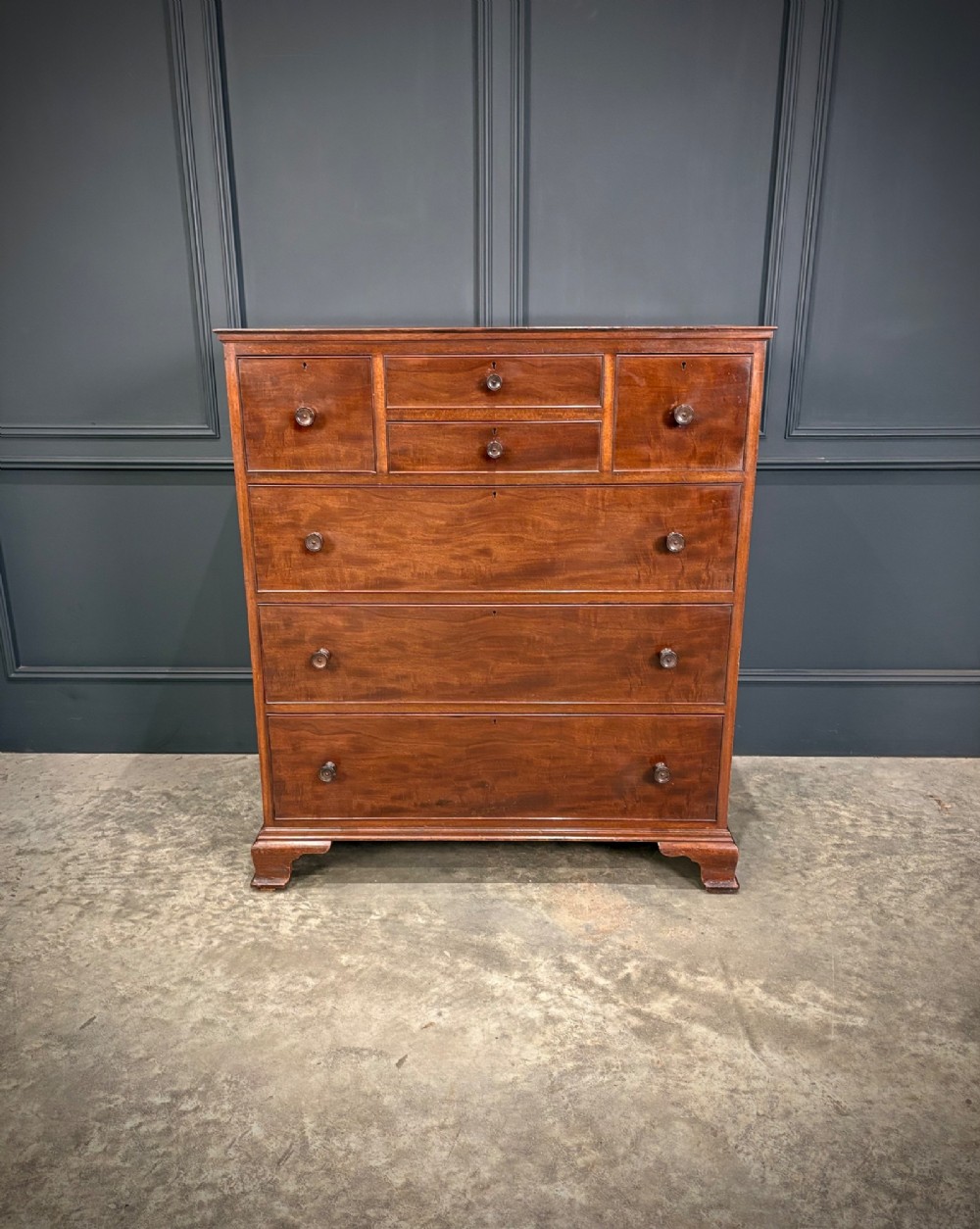 A tall antique mahogany chest of drawers featuring an upper arrangement of small drawers over three graduated full-width drawers, resting on bracket feet. View IV