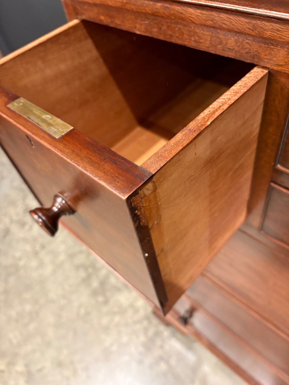 A tall antique mahogany chest of drawers featuring an upper arrangement of small drawers over three graduated full-width drawers, resting on bracket feet. View VII