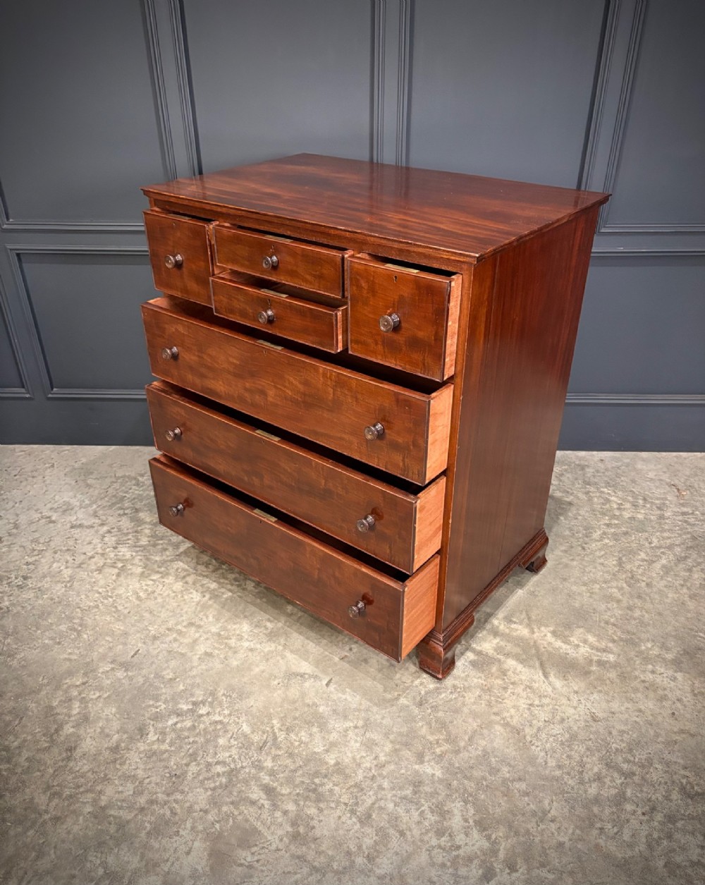 A tall antique mahogany chest of drawers featuring an upper arrangement of small drawers over three graduated full-width drawers, resting on bracket feet. View IX