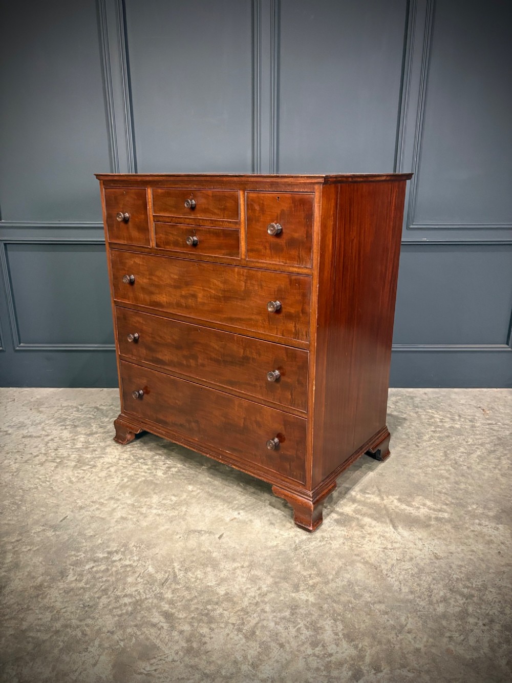 A tall antique mahogany chest of drawers featuring an upper arrangement of small drawers over three graduated full-width drawers, resting on bracket feet. View XI