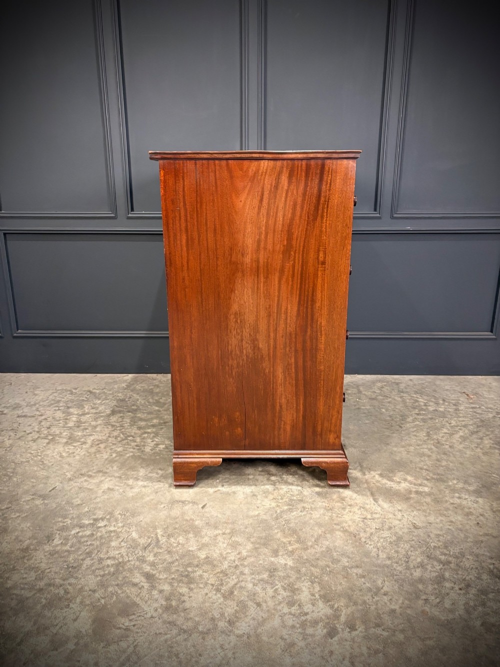 A tall antique mahogany chest of drawers featuring an upper arrangement of small drawers over three graduated full-width drawers, resting on bracket feet. View XIV