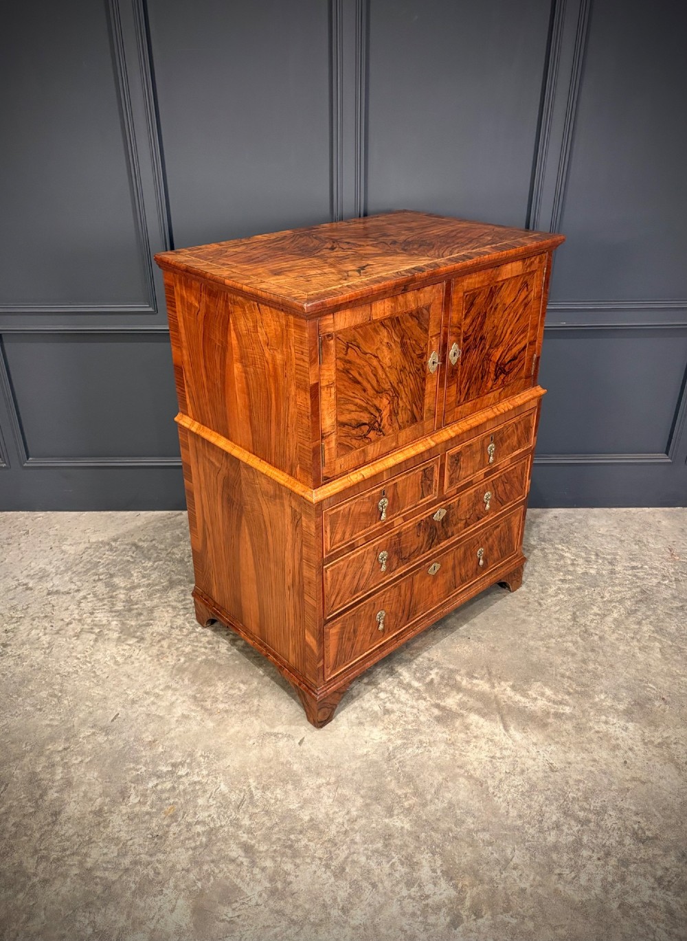 An antique walnut cabinet on chest featuring a twin-door top cupboard over graduating drawers with brass hardware and bracket feet. View II