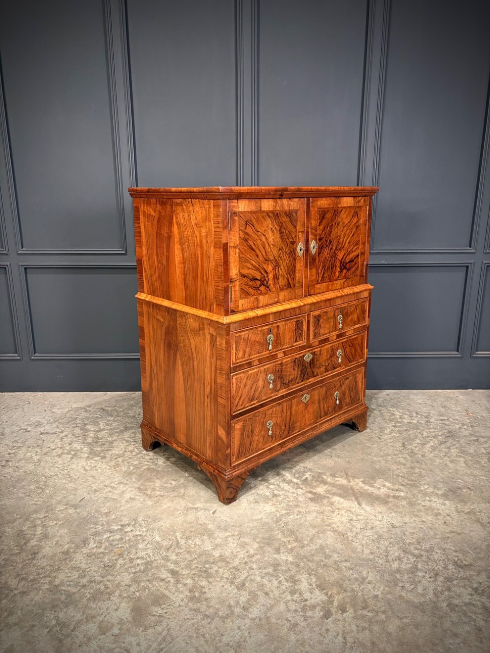 An antique walnut cabinet on chest featuring a twin-door top cupboard over graduating drawers with brass hardware and bracket feet. View III