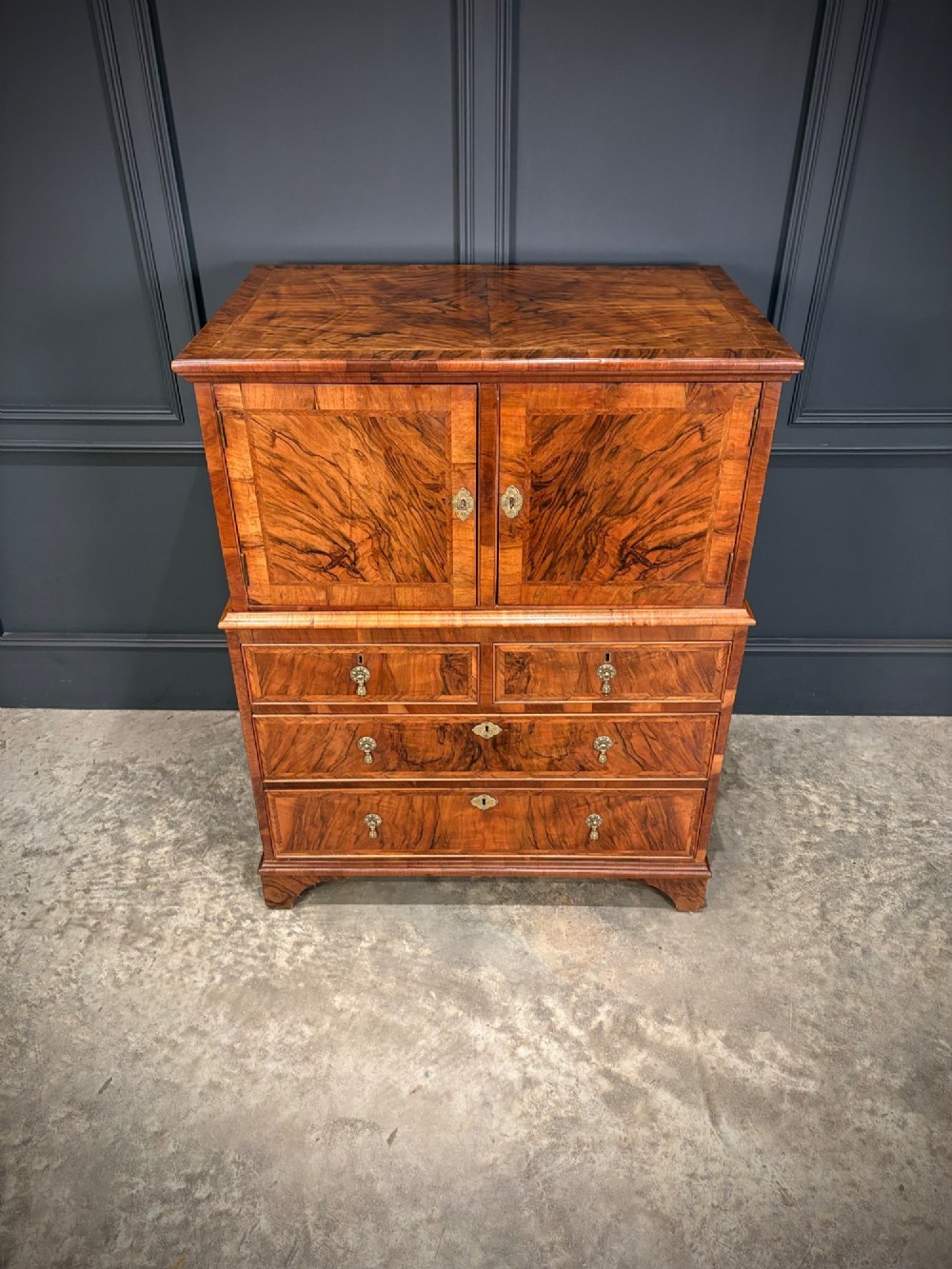 An antique walnut cabinet on chest featuring a twin-door top cupboard over graduating drawers with brass hardware and bracket feet. View IV
