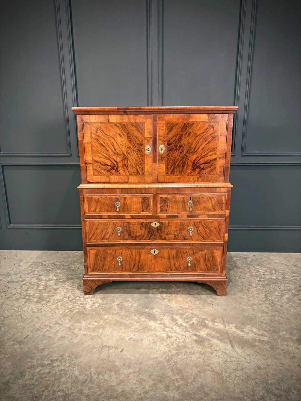 An antique walnut cabinet on chest featuring a twin-door top cupboard over graduating drawers with brass hardware and bracket feet. View V