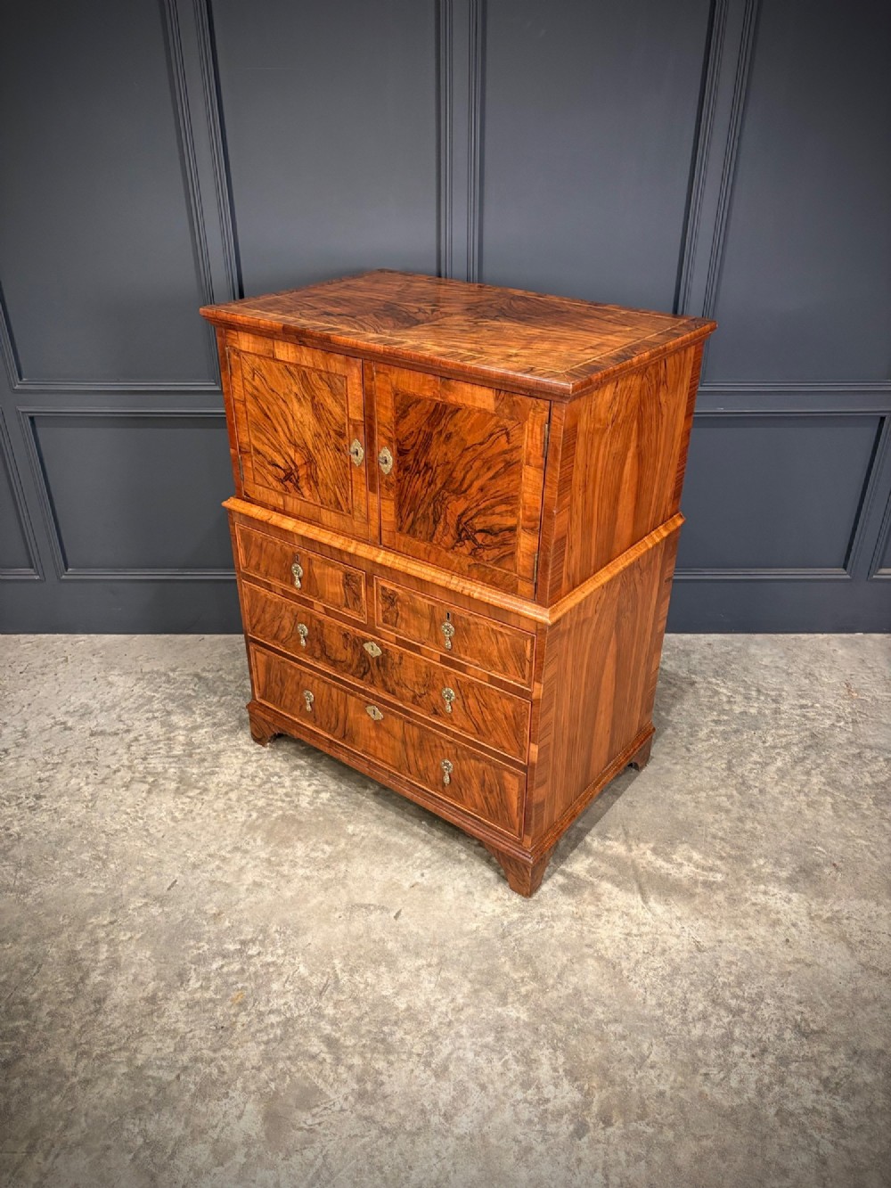 An antique walnut cabinet on chest featuring a twin-door top cupboard over graduating drawers with brass hardware and bracket feet. View VII