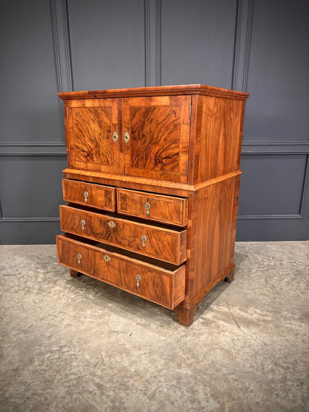 An antique walnut cabinet on chest featuring a twin-door top cupboard over graduating drawers with brass hardware and bracket feet. View VIII