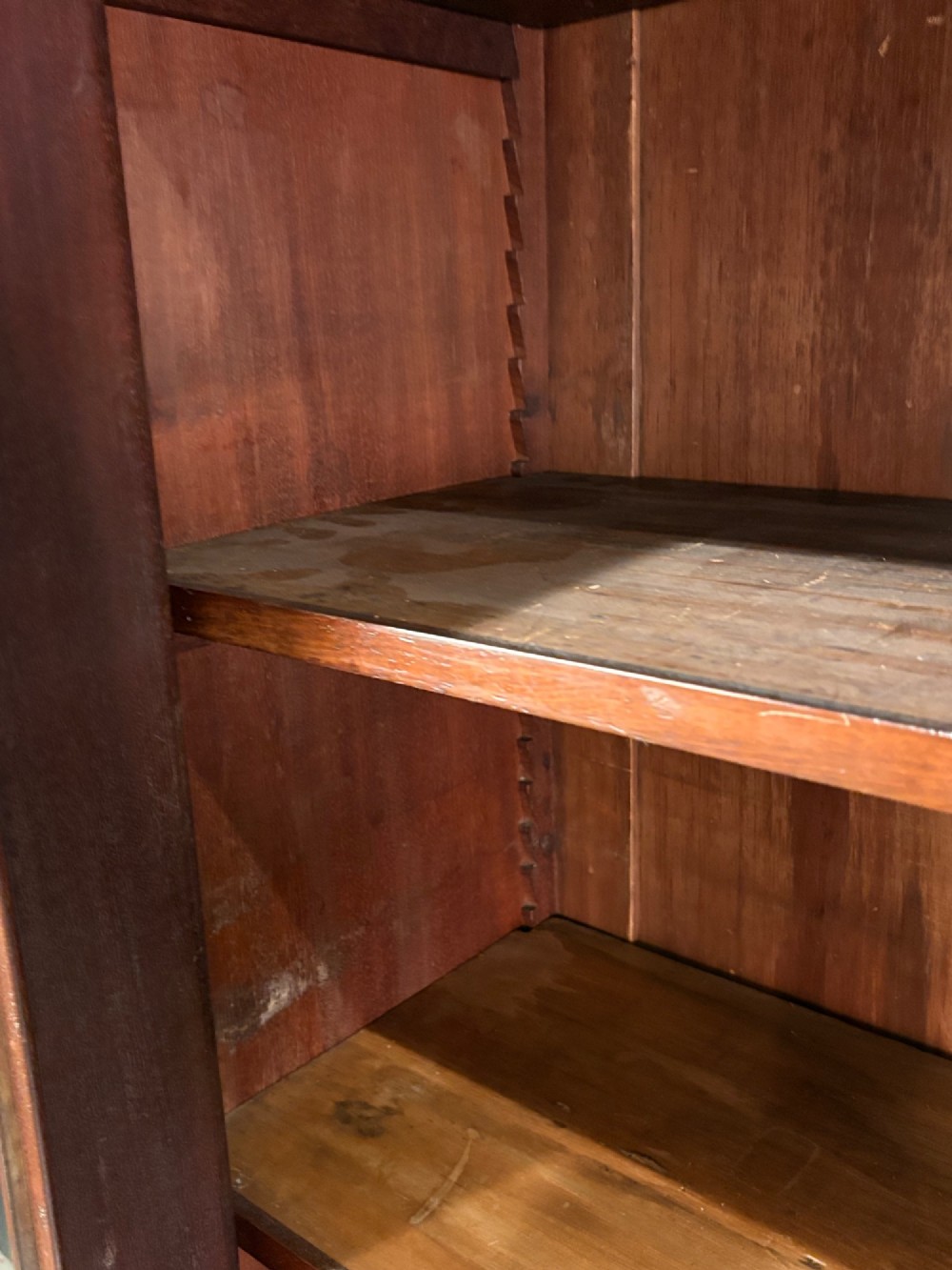 A large Victorian mahogany bookcase featuring two arched glazed doors, carved corbels, internal wooden shelves, and two drawers at the base. View VI