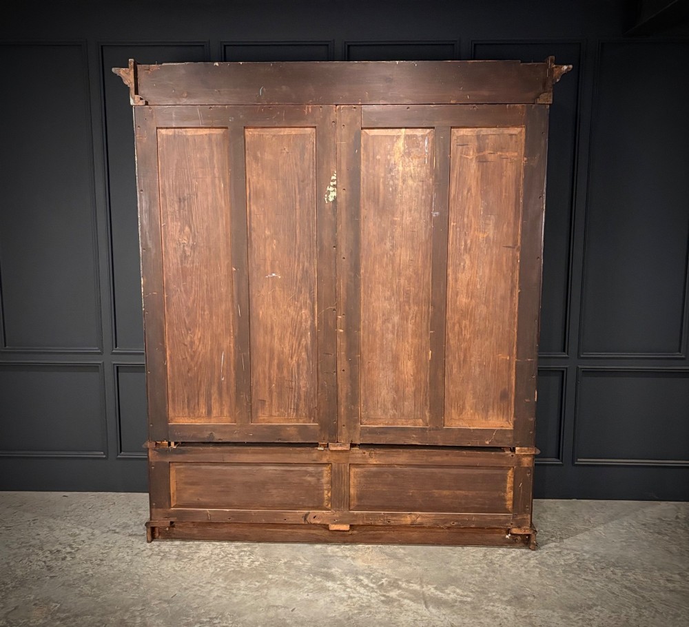 A large Victorian mahogany bookcase featuring two arched glazed doors, carved corbels, internal wooden shelves, and two drawers at the base. View VII