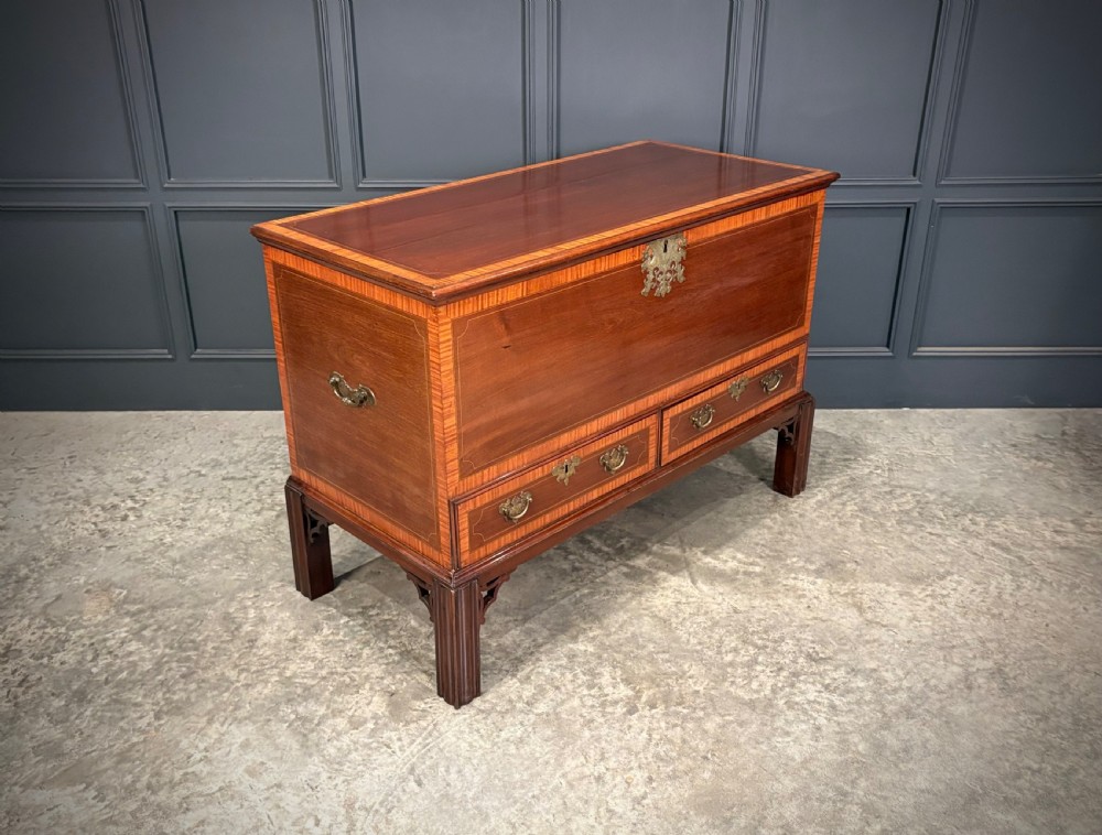 A Georgian inlaid mahogany silver chest on stand featuring satinwood crossbanding, brass side carrying handles, two lower drawers, and square legs with bracket corner supports.