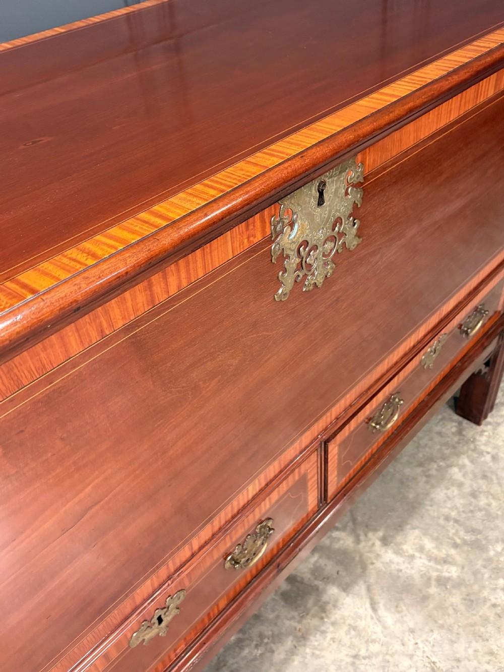 A Georgian inlaid mahogany silver chest on stand featuring satinwood crossbanding, brass side carrying handles, two lower drawers, and square legs with bracket corner supports. View IV