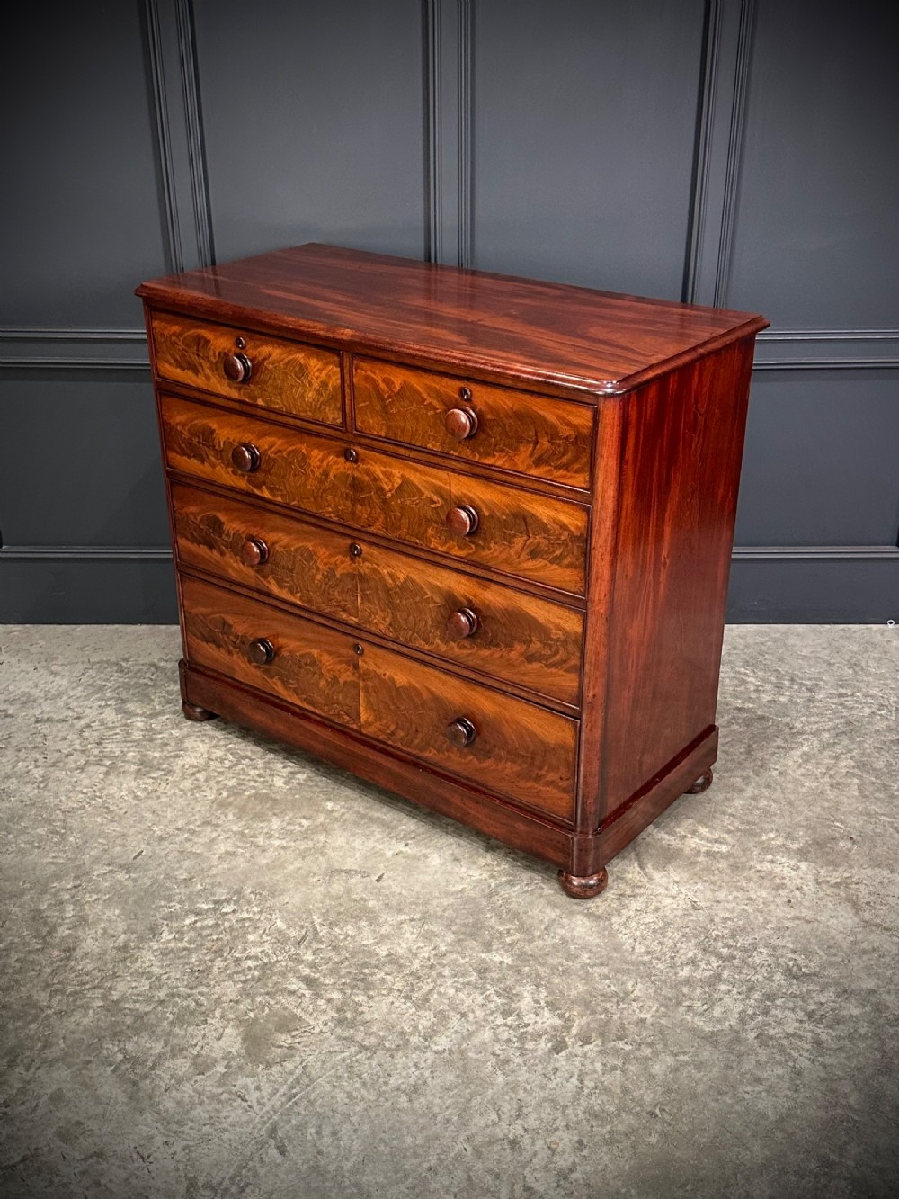 A Victorian mahogany chest of drawers featuring a two short over three long drawer arrangement with turned wood handles and flame mahogany grain patterns. View II