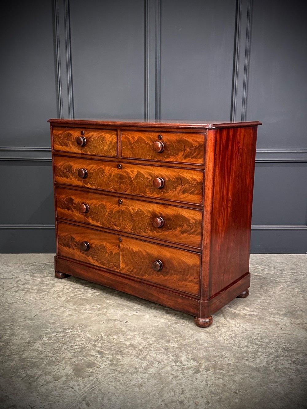 A Victorian mahogany chest of drawers featuring a two short over three long drawer arrangement with turned wood handles and flame mahogany grain patterns. View III