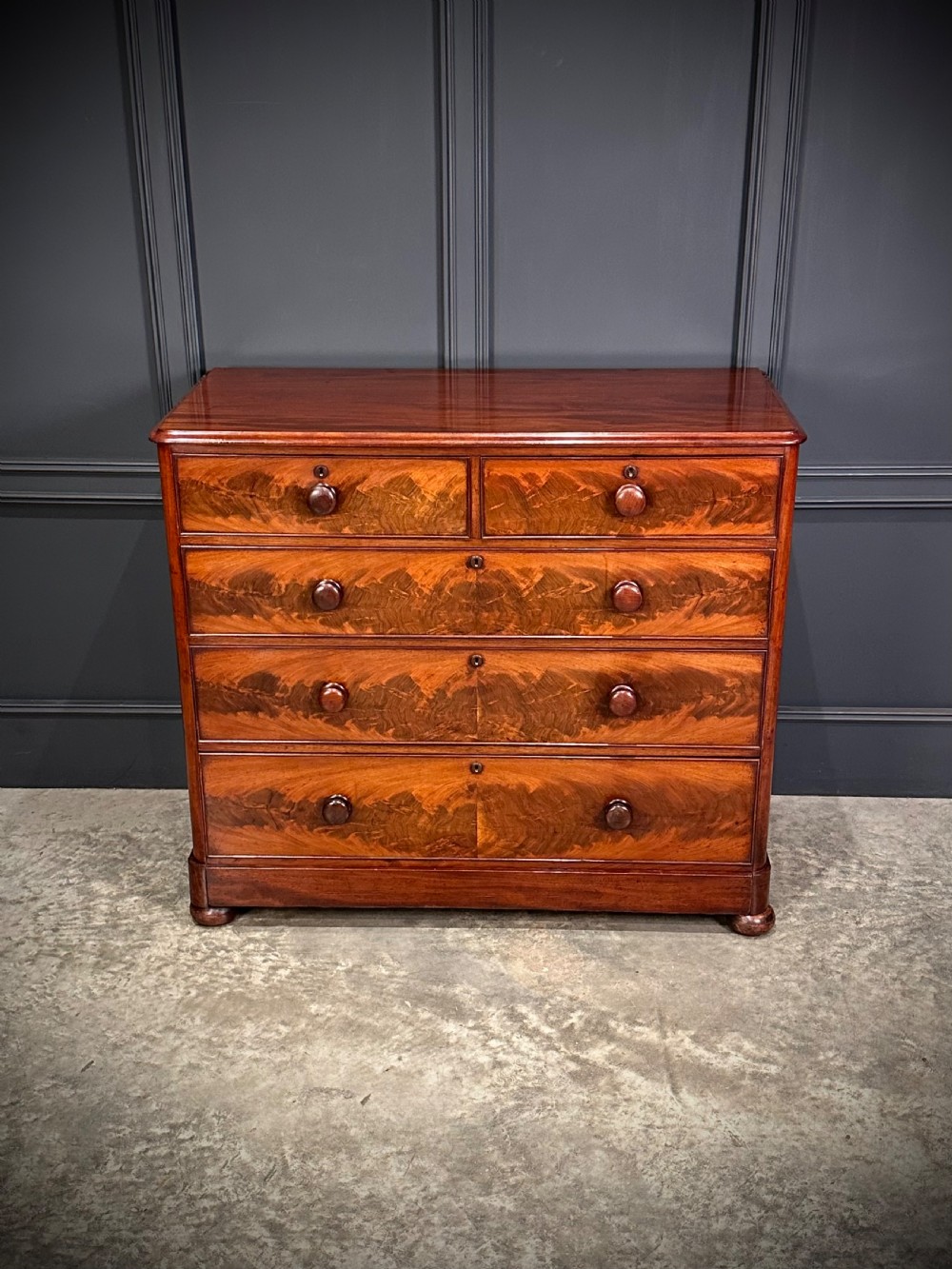 A Victorian mahogany chest of drawers featuring a two short over three long drawer arrangement with turned wood handles and flame mahogany grain patterns. View IV