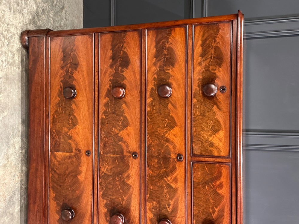 A Victorian mahogany chest of drawers featuring a two short over three long drawer arrangement with turned wood handles and flame mahogany grain patterns. View VI