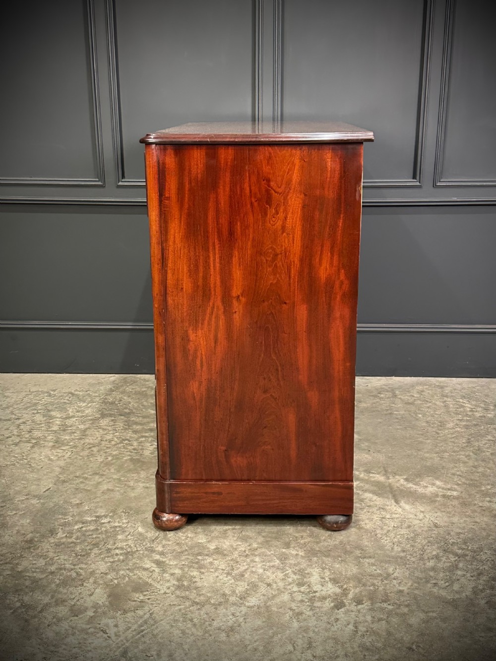 A Victorian mahogany chest of drawers featuring a two short over three long drawer arrangement with turned wood handles and flame mahogany grain patterns. View X