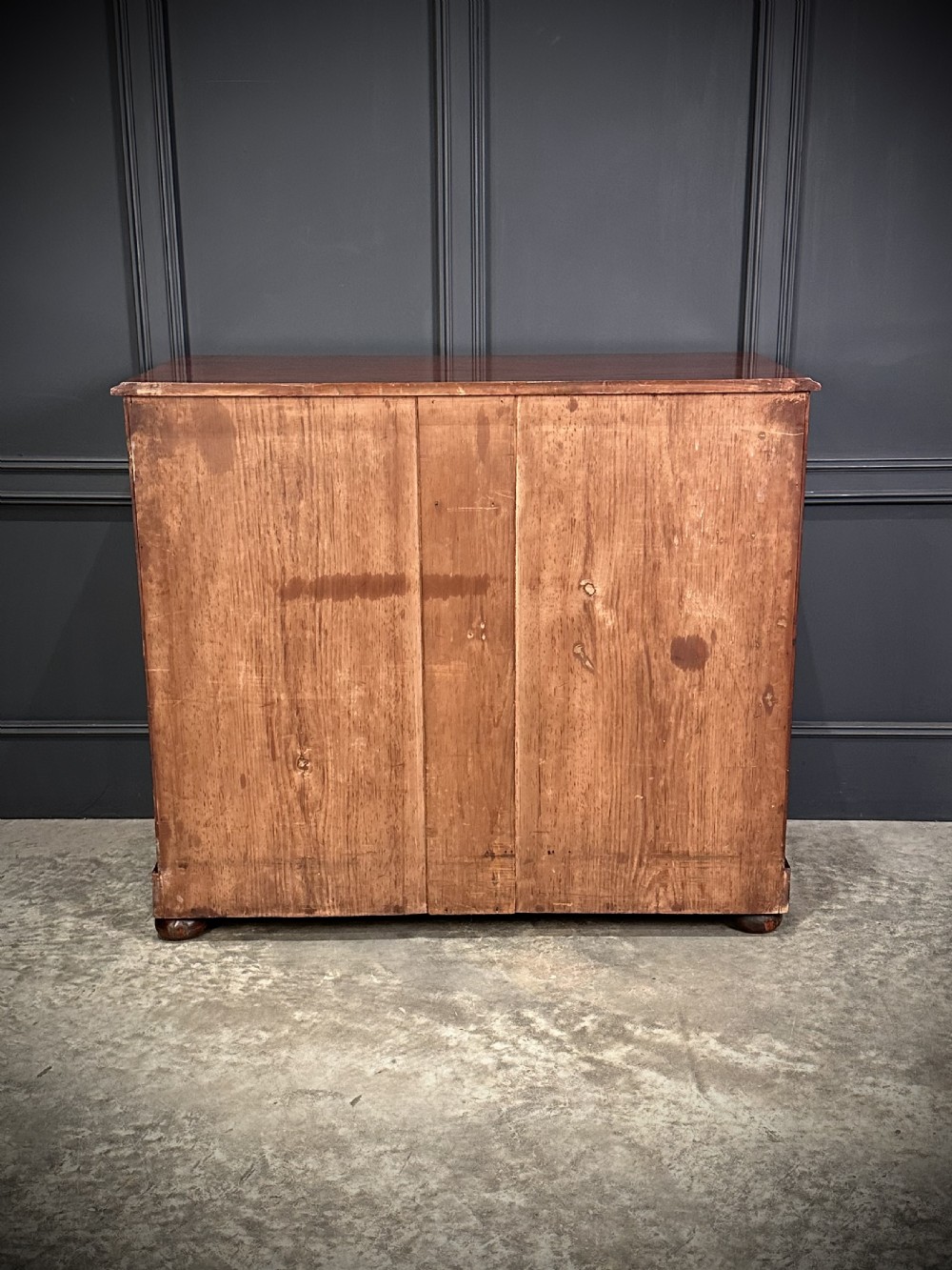 A Victorian mahogany chest of drawers featuring a two short over three long drawer arrangement with turned wood handles and flame mahogany grain patterns. View XI