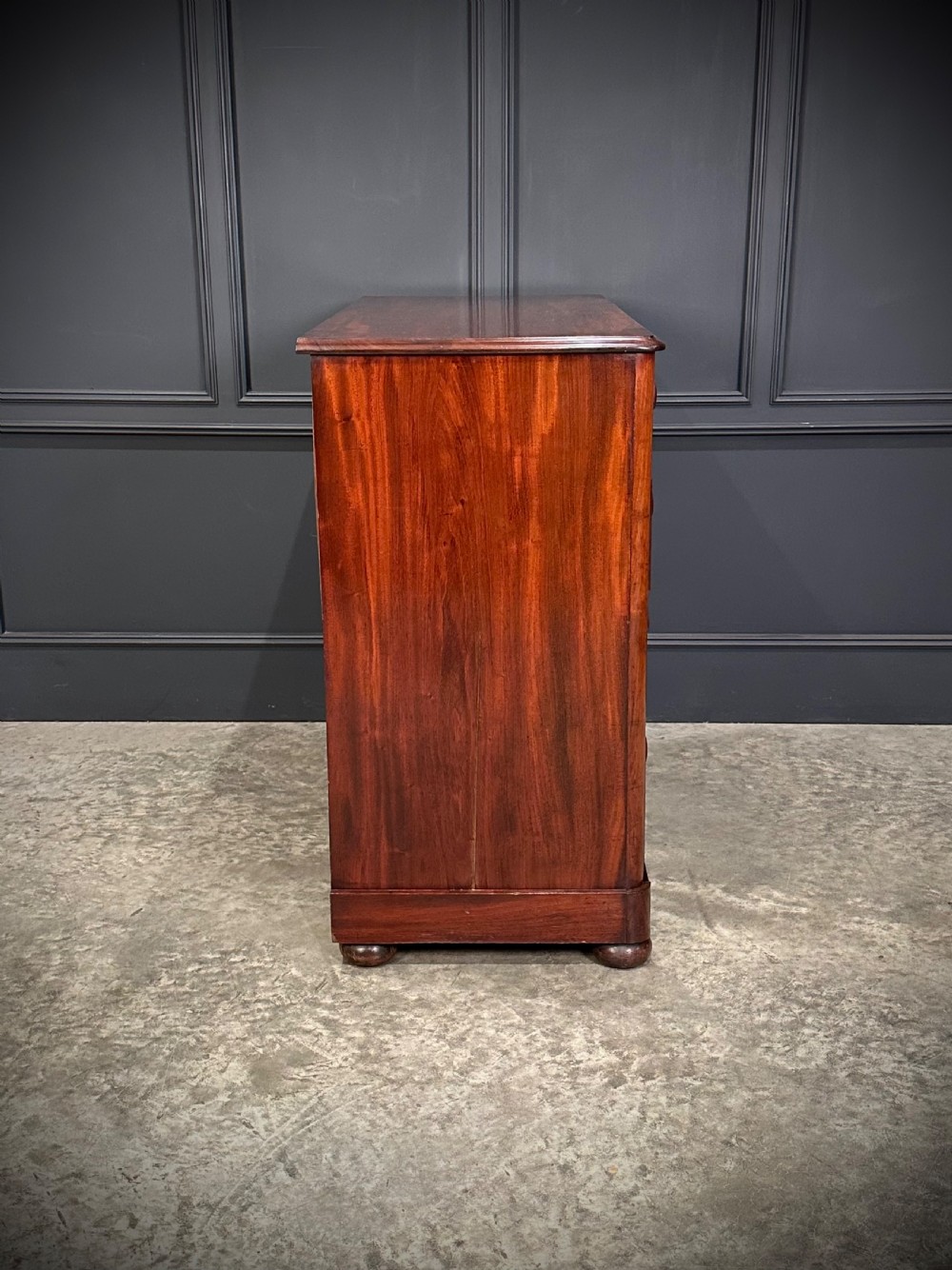 A Victorian mahogany chest of drawers featuring a two short over three long drawer arrangement with turned wood handles and flame mahogany grain patterns. View XII